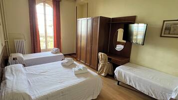 Une chambre d’hôtel avec deux lits simples, une armoire, un miroir, une télévision et un radiateur.