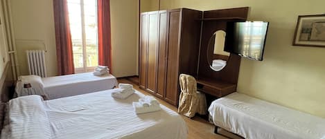 Habitación de hotel con dos camas individuales, un armario, un espejo, un televisor y un radiador.