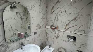 A bathroom with a large sink, a bidet, and a mirror.