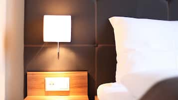 A neatly made bed with a dark headboard and a bedside table with a lamp.