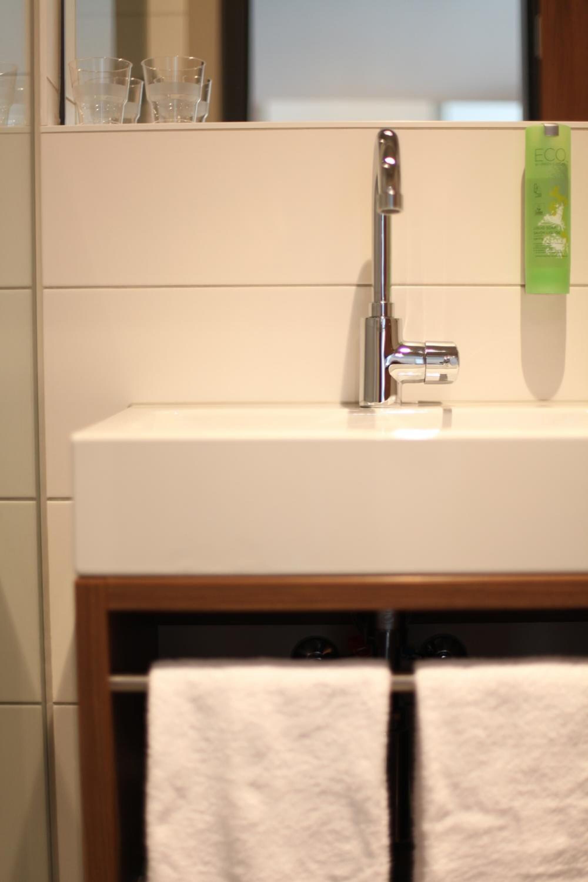 A bathroom with a white sink, a mirror, and two towels hanging on a rack.