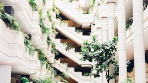 A multi-level atrium with a central staircase surrounded by lush greenery and white columns. - Spring Arona Gran Hotel & SPA - Adults Only (Arona)