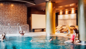 A swimming pool area with multiple people, a stone wall, and lounge chairs. - Spring Arona Gran Hotel & SPA - Adults Only (Arona)
