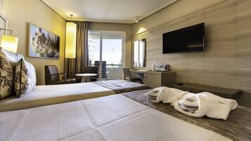Habitación de hotel con dos camas, un escritorio, una silla, un televisor y una ventana con vistas.