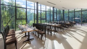 Un vaste espace dédié à la salle à manger, doté de grandes fenêtres, de nombreuses tables dressées et de rangées de chaises.
