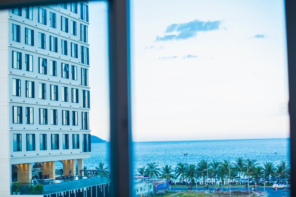 Un hôtel moderne doté d’une grande façade en verre, d’un espace piscine et d’une vue sur l’océan.