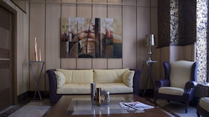 Una sala de estar moderna con sofá, sillón, mesa de centro y arte abstracto en la pared.