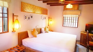 A bedroom with a large bed, wooden headboard, and two bedside lamps. - Cat Tuong Boutique Villas (Da Nang)
