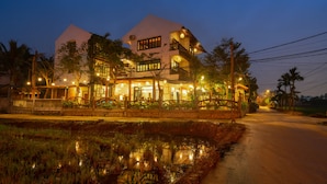 A two-story building with a balcony, a covered walkway, and a pond in front. - Cat Tuong Boutique Villas (Da Nang)