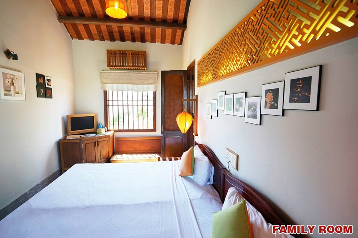 Une salle familiale avec un grand lit, des meubles en bois et des tableaux accrochés au mur.