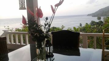 Una mesa con un jarrón de flores, un farol y vista al mar.