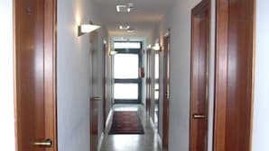 A hallway with wooden doors, a red patterned rug, and a marble floor. - Hotel Excelsior (Latina)