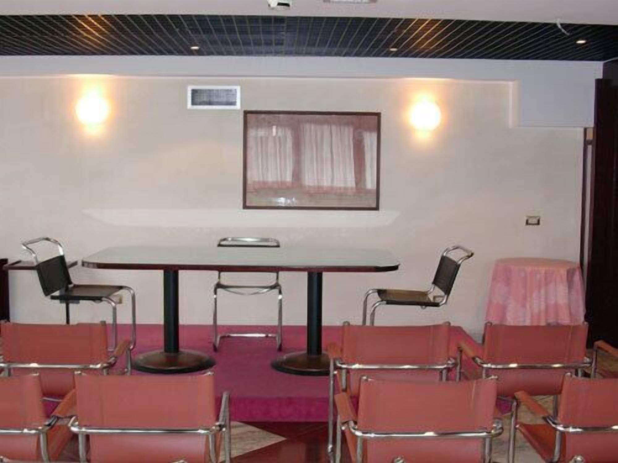 A conference room with a table and chairs, a framed picture on the wall, and a pink tablecloth on a side table.