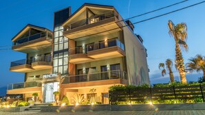 Un hotel de varios pisos con un llamativo letrero que dice "PRINCIPAL", balcones y una entrada bien iluminada.