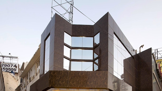 A modern building with a prominent entrance, large windows, and a parking area in front. - Hotel Aura, IGI Airport (New Delhi)