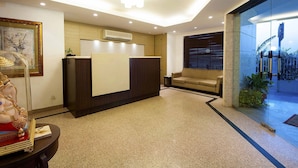 A reception area with a reception desk, a sofa, and a statue. - Hotel Aura, IGI Airport (New Delhi)