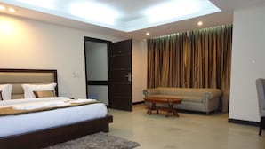 A modern hotel room with a large bed, a sofa, a small table, and a mirror. - Hotel Aura, IGI Airport (New Delhi)
