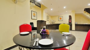 A dining area with a round table, two chairs, and a buffet counter in the background. - Hotel Aura, IGI Airport (New Delhi)