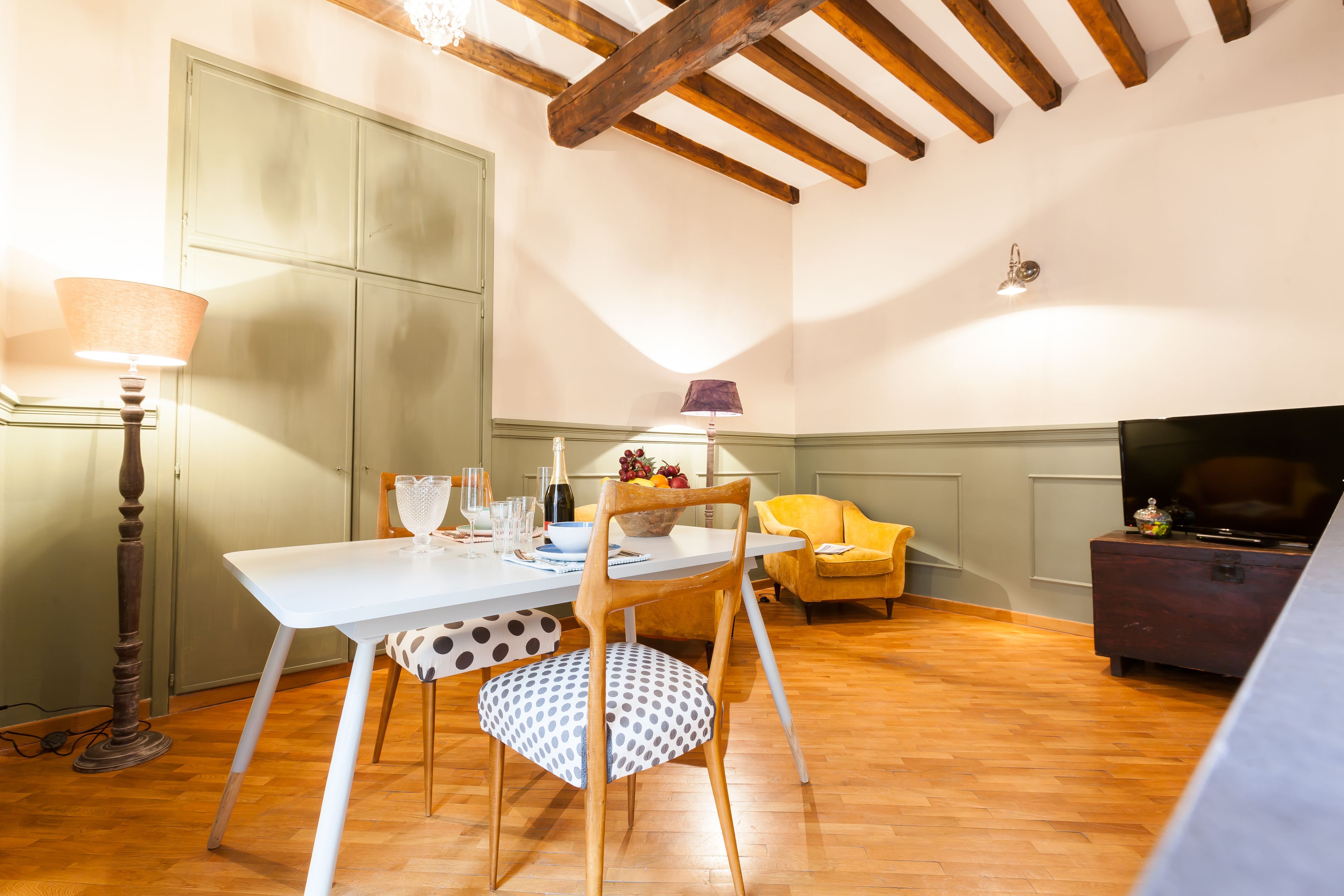 A dining area with a white table, chairs, and a wooden ceiling.
