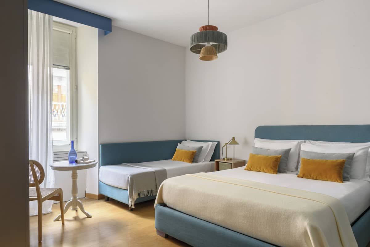 Ein Hotelzimmer mit zwei Betten, einem kleinen Tisch, einem Stuhl und einer Pendelleuchte.