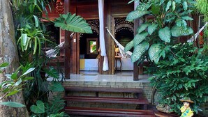 A wooden staircase leading to a porch with a hammock and a statue. - Pousada Riacho dos Cambucás (Angra dos Reis)