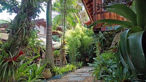 A tropical garden pathway with various plants and a wooden structure in the background. - Pousada Riacho dos Cambucás (Angra dos Reis)