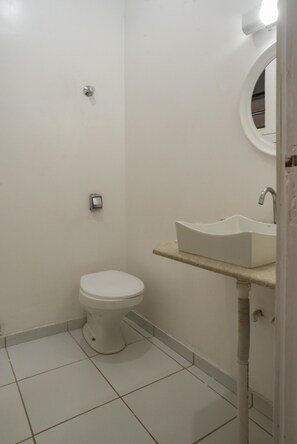 Ein kleines, sauberes Badezimmer mit Toilette, Waschbecken und Spiegel.