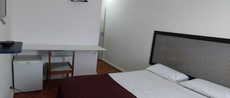 Un dormitorio con cama, escritorio, silla y lámpara colgante.