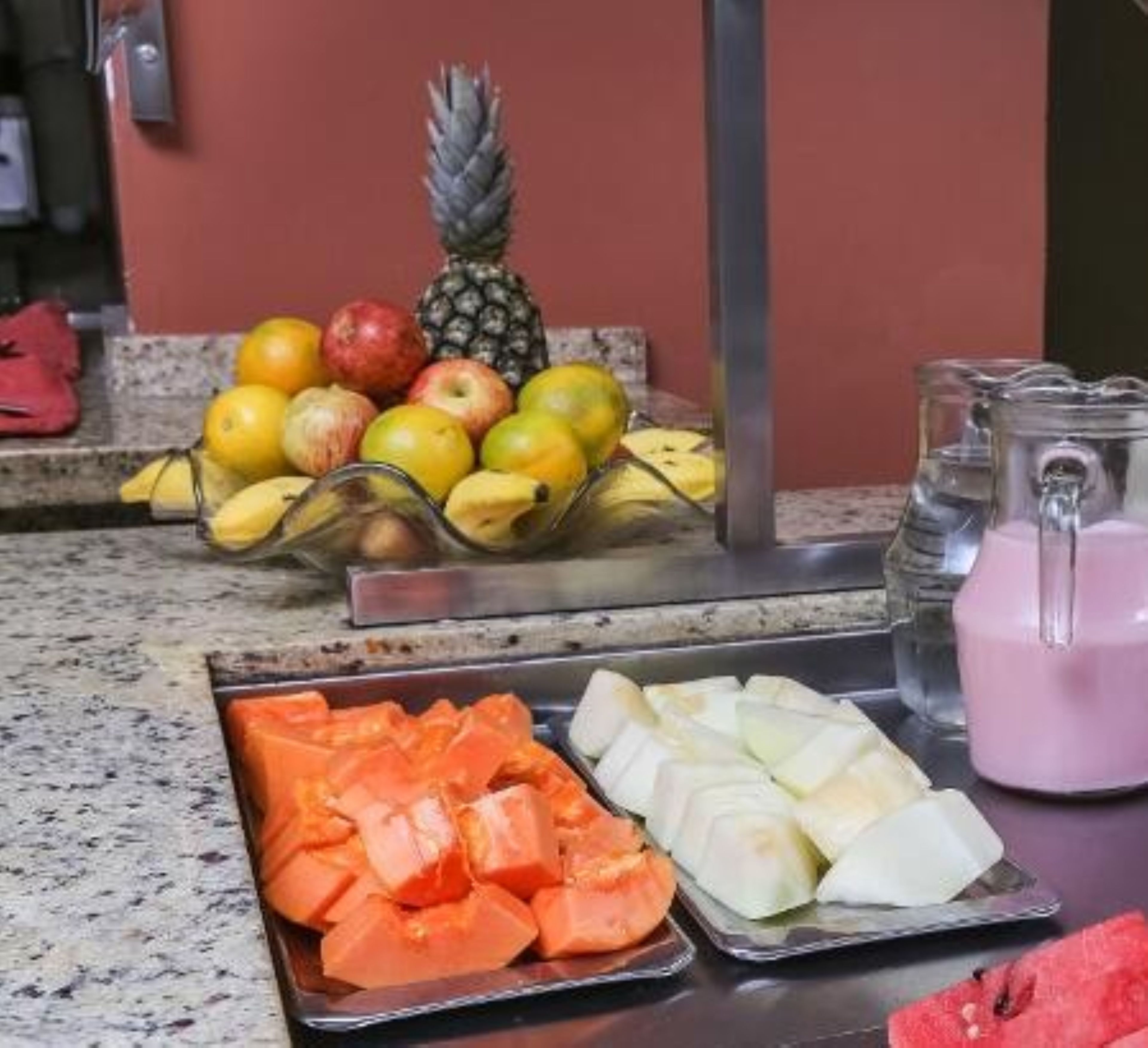 Exposição de frutas com maçãs, bananas e uma abacaxi.