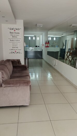 Een moderne hotellobby met een receptiebalie, een bank en een glazen scheidingswand.