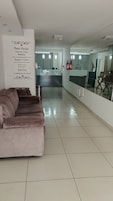 Un vestíbulo moderno de hotel con una recepción, un sofá y un panel de vidrio.