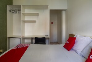 A bedroom with a bed, a desk, and a chair. There is a small refrigerator and a closet with shelves. - Palace Hotel Campo Grande (Campo Grande)