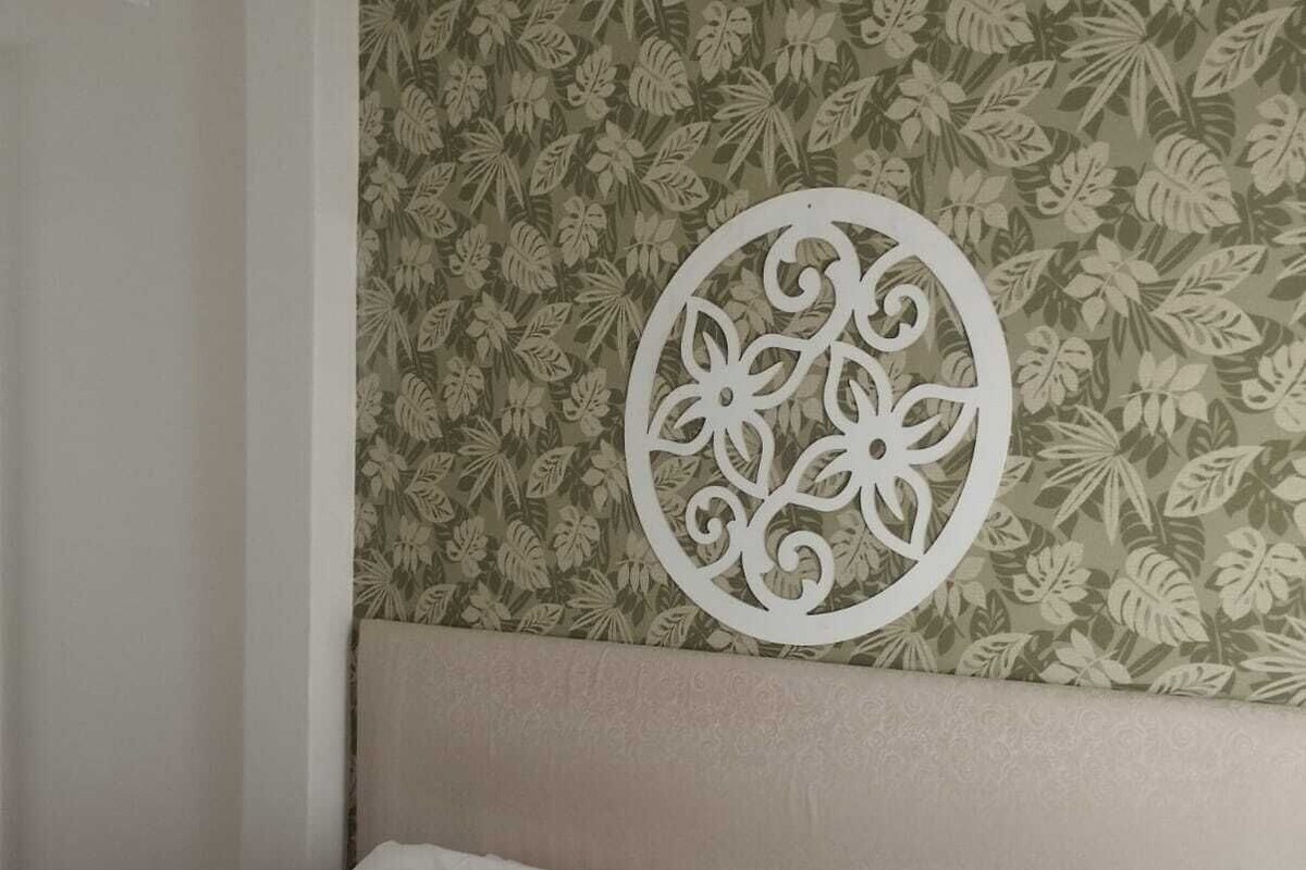 Ein Hotelzimmer mit einem Bett, zwei Kissen, einem Kopfteil und einer dekorativen Wandverkleidung.