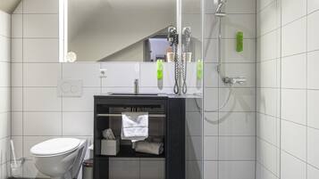 Un baño moderno con cabina de ducha de vidrio, inodoro y tocador con espejo.