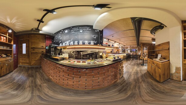 A circular counter with a brick base, surrounded by wooden cabinets and shelves with various items.