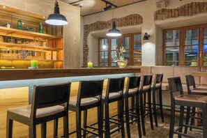 A bar area with wooden shelves, bar stools, and pendant lighting.
