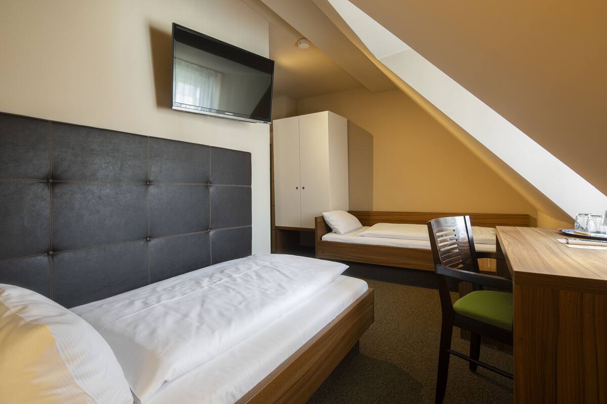 Een slaapkamer met een groot bed, een kleiner bed, een bureau en een stoel.