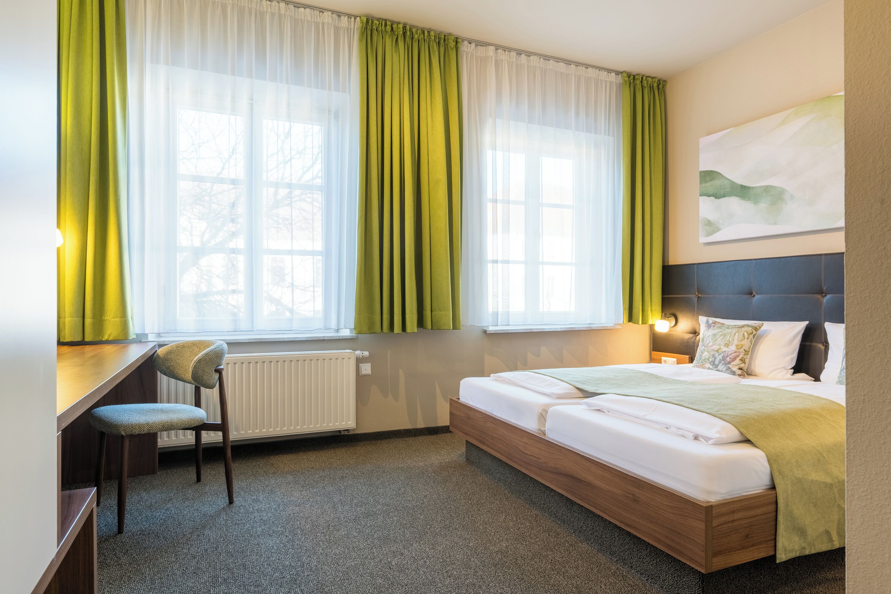 A bedroom with a bed, a desk, and a chair.