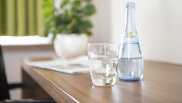 A clear glass of water and a clear bottle on a wooden table.