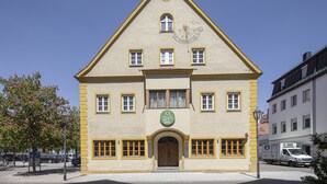 A two-story building with a clock on the facade, a sign for Joe's Swiss Hotel, and a large wooden door.