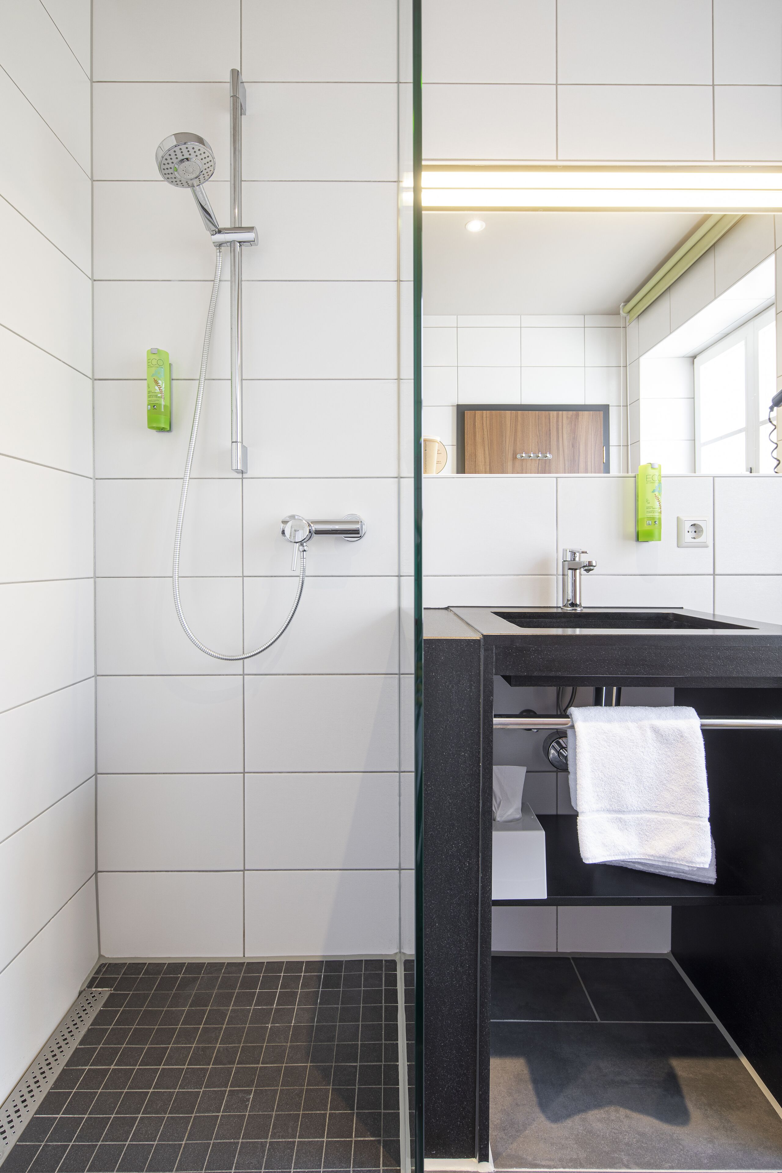 Ein modernes Badezimmer mit Dusche, Waschbecken und Spiegel.