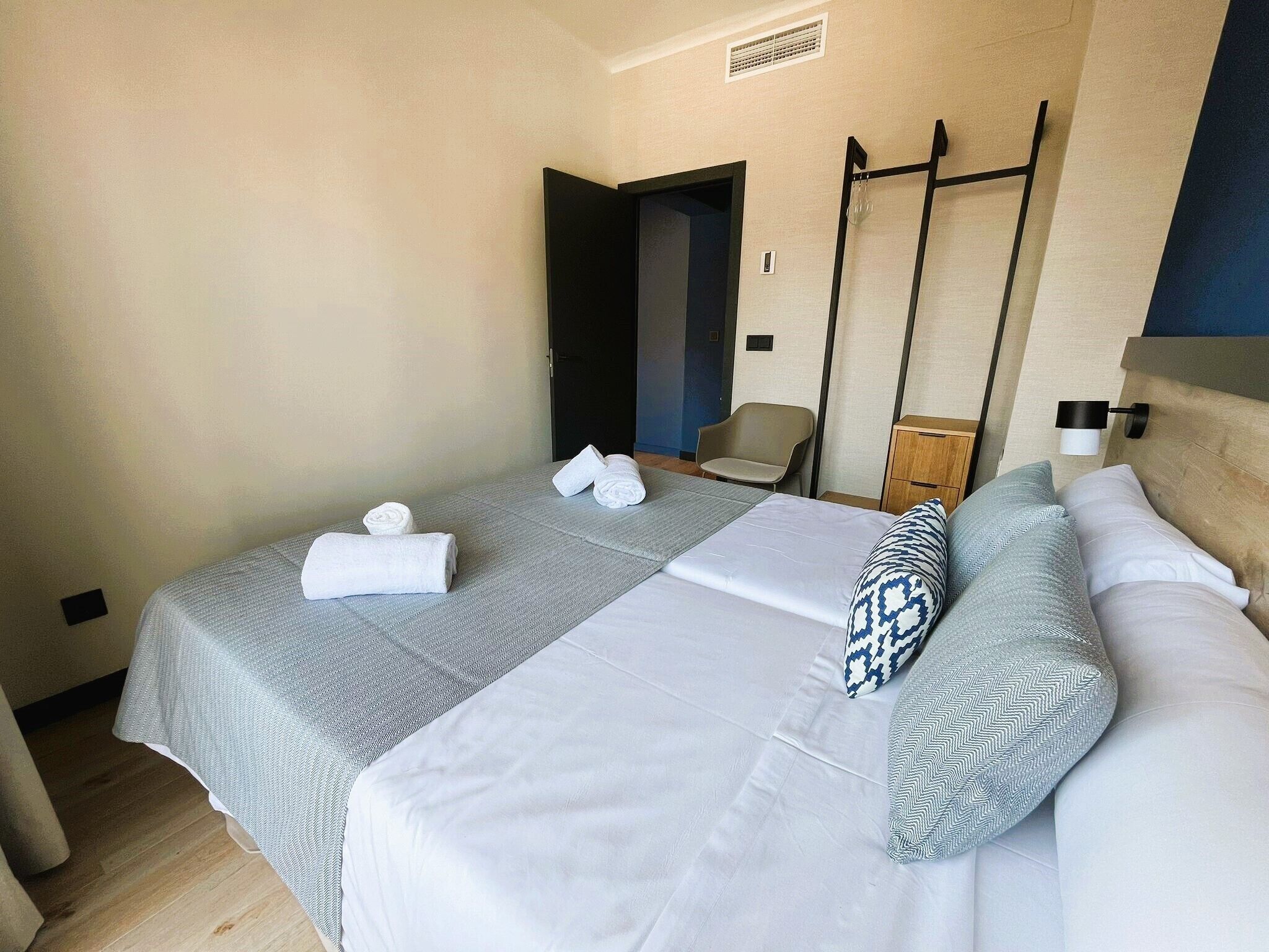 Hotellihuone, jossa on kaksi sänkyä, tuoli, pieni pöytä ja vaatekaappi.