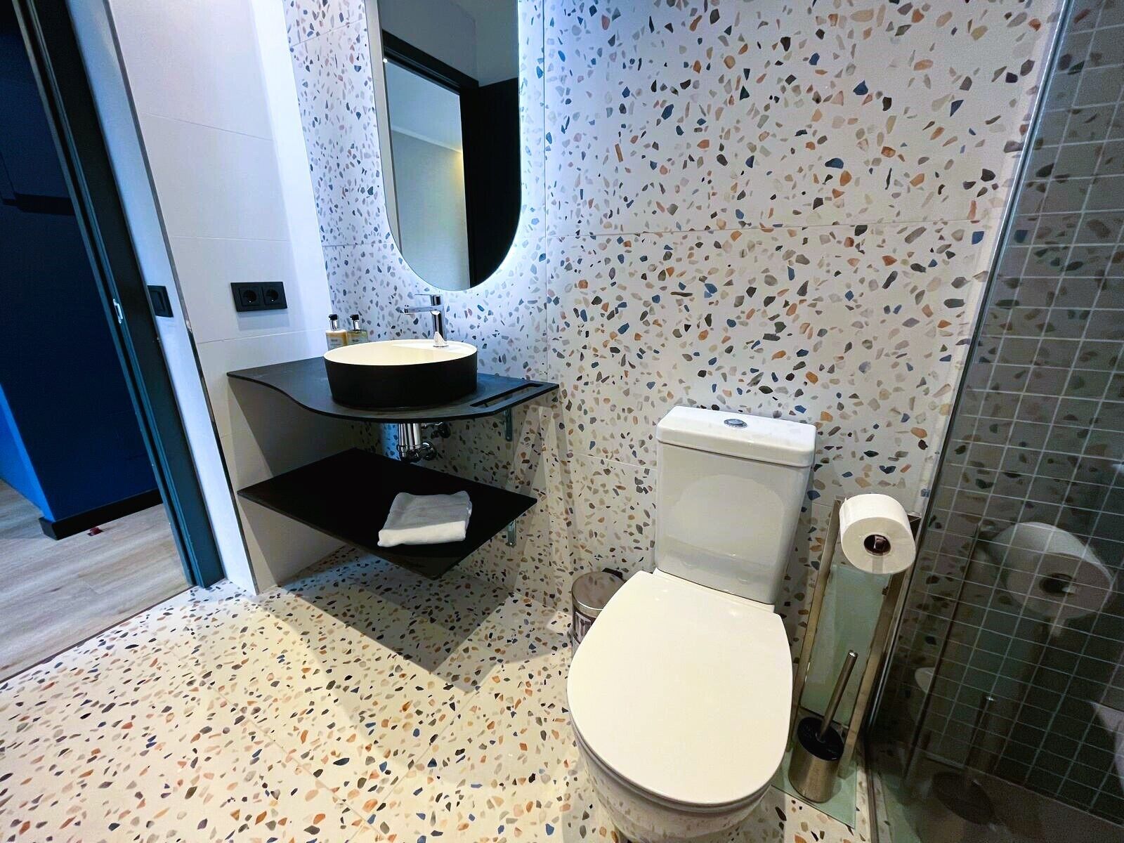 Un baño moderno con un lavabo redondo, inodoro y zona de ducha.