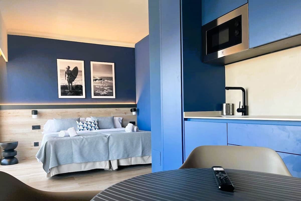 Une chambre d’hôtel moderne avec un lit, une table ronde, un téléviseur et des œuvres d’art accrochées au mur.