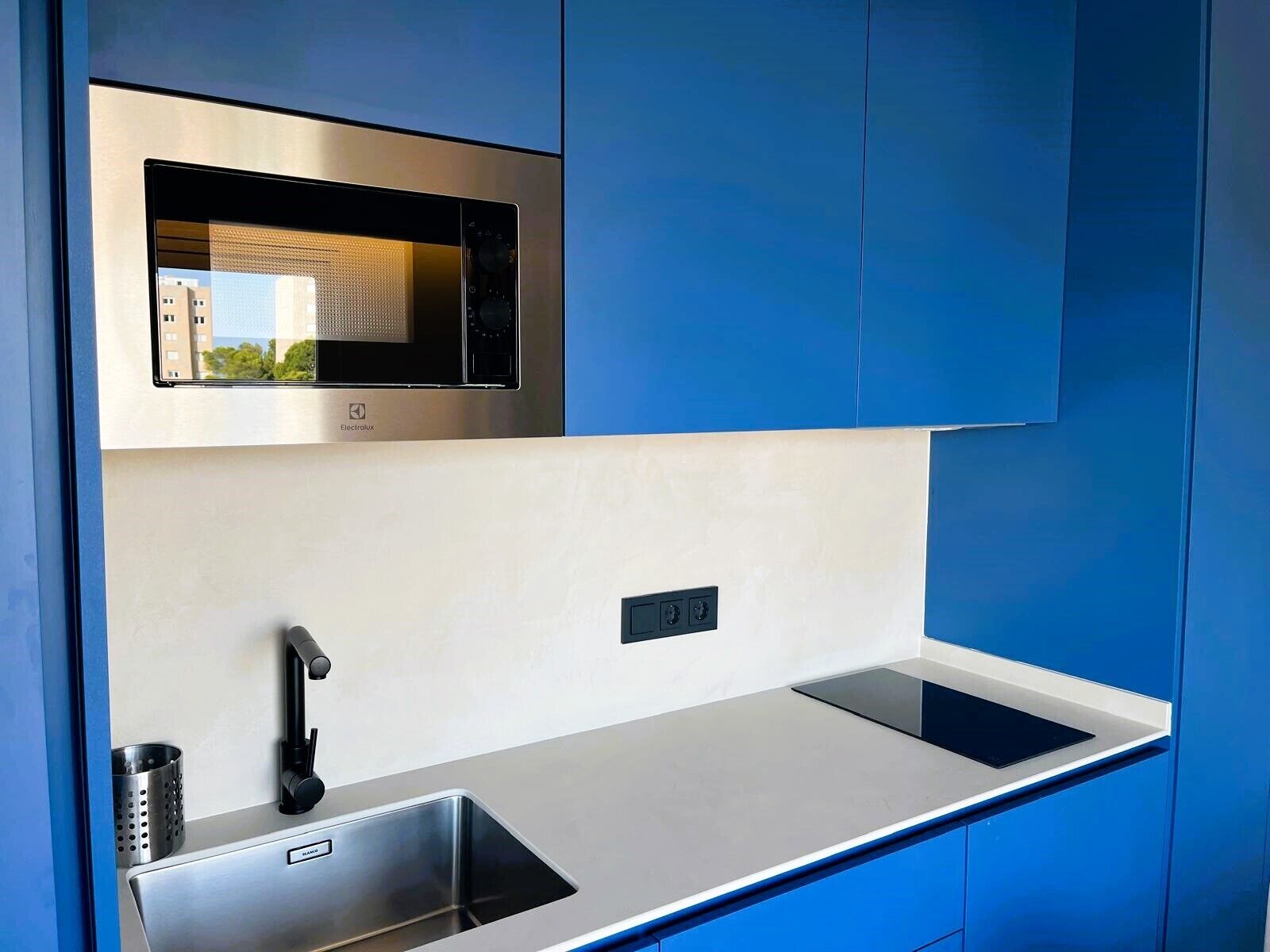 A compact kitchen with a built-in microwave, a sink, and a faucet.