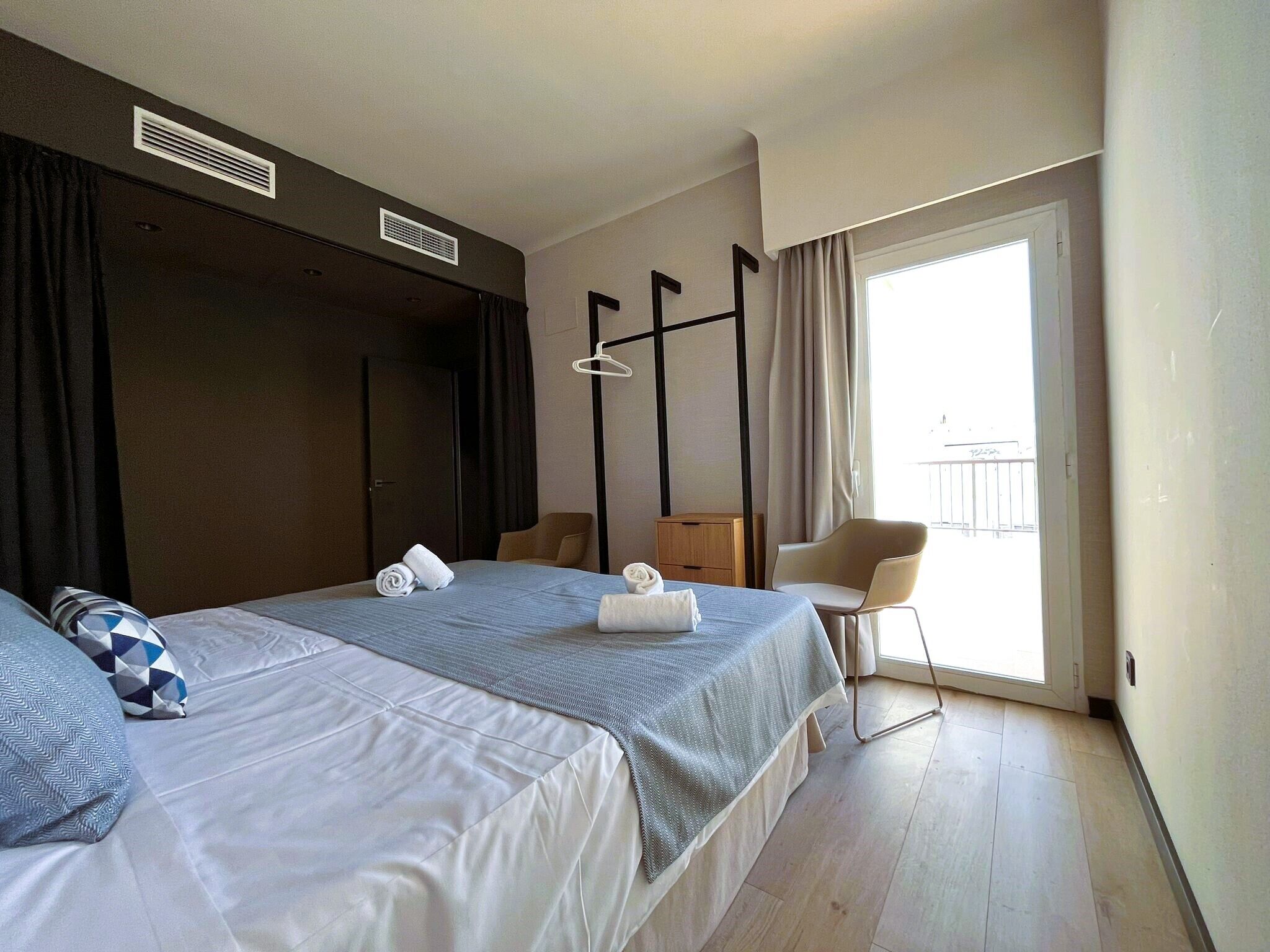 Une chambre d’hôtel avec deux lits, une chaise, une armoire et un balcon.