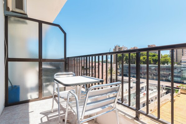 Enjoy the city view from this balcony with a table and chairs.