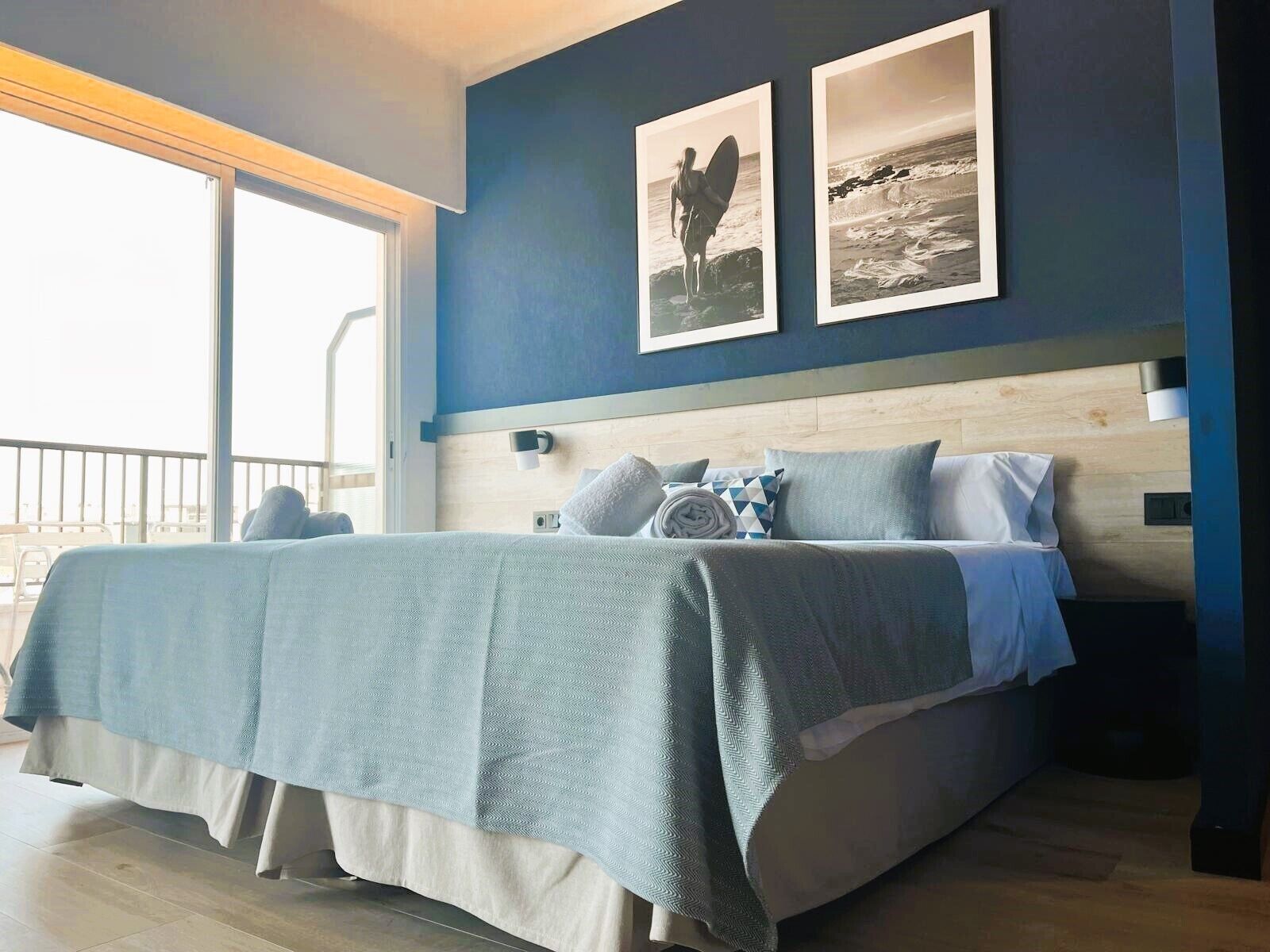 Ein modernes Schlafzimmer mit einem großen Bett, einem Holzkopfstück und Meerblick durch ein großes Fenster.