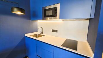 A modern kitchen with blue cabinetry, a stainless steel sink, and a built-in microwave.