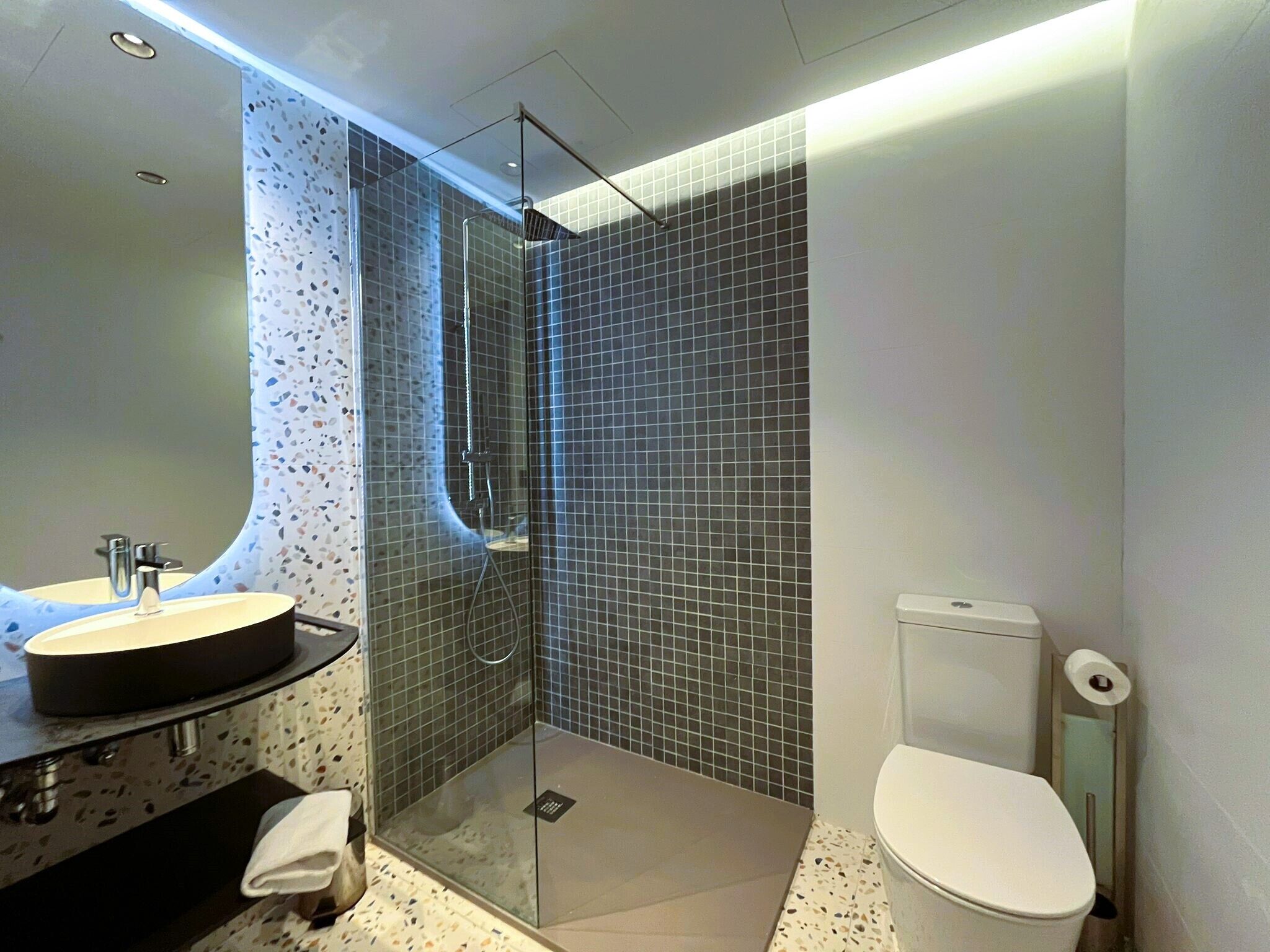 A modern bathroom with a glass-enclosed shower, a round sink, and a toilet.